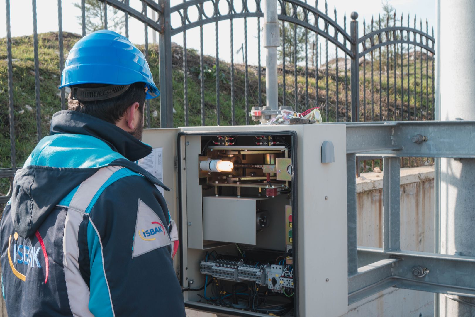 Electrician in a hard hat inspecting a distribution panel