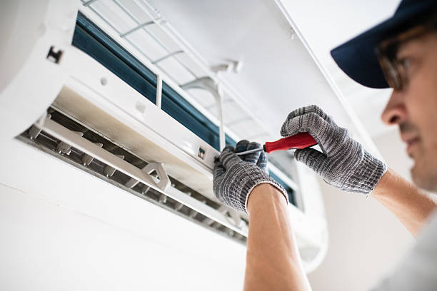 Technician inspecting the inside of an air conditioning unit