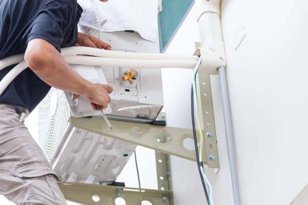 Technician in safety gear mounting a split AC unit indoors